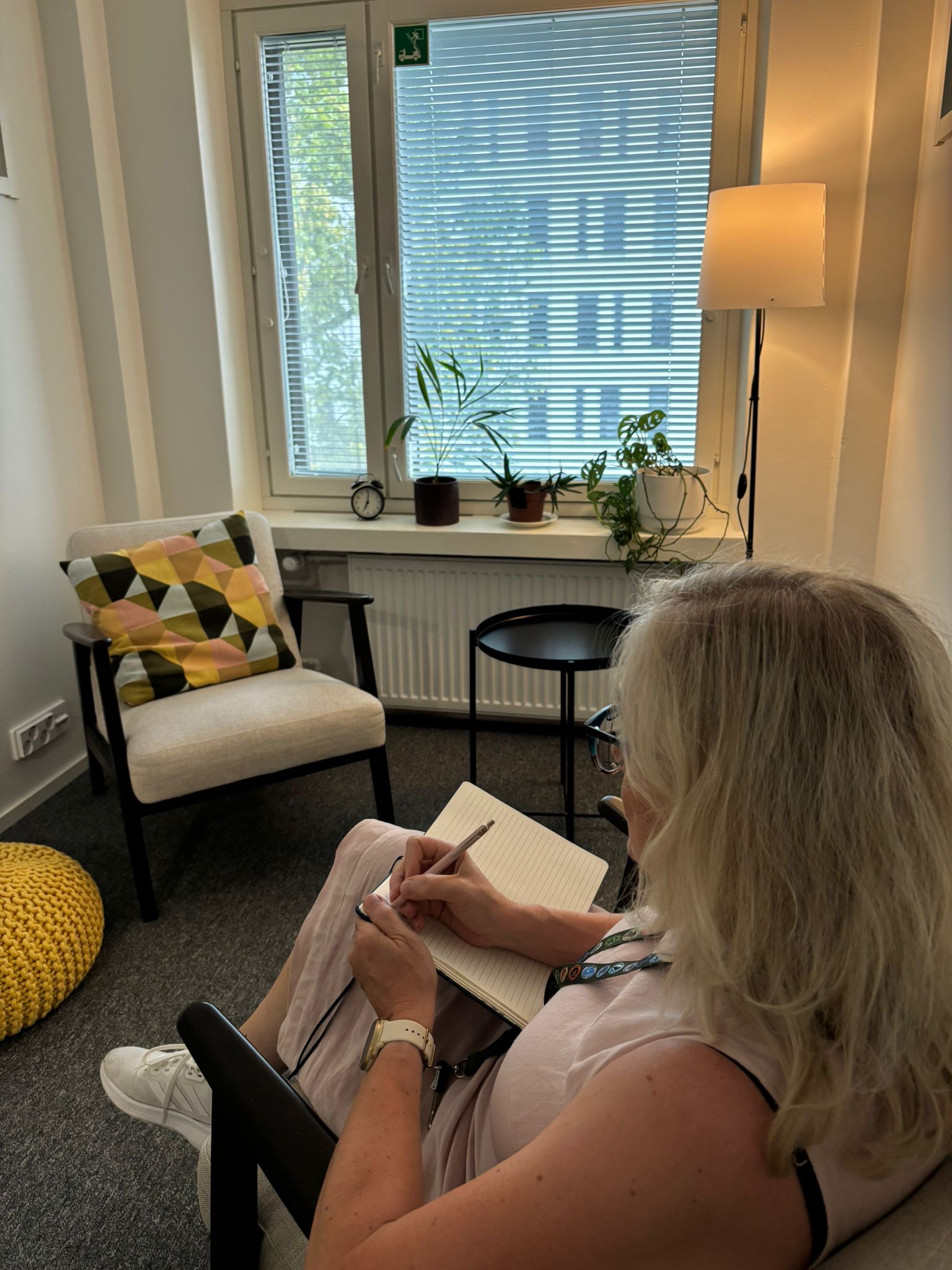 Lyhytterapeutti kirjoittamassa muistiinpanoja rauhallisessa vastaanottohuoneessa